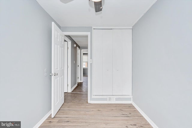 unfurnished bedroom with baseboards, ceiling fan, a closet, and light wood-style floors