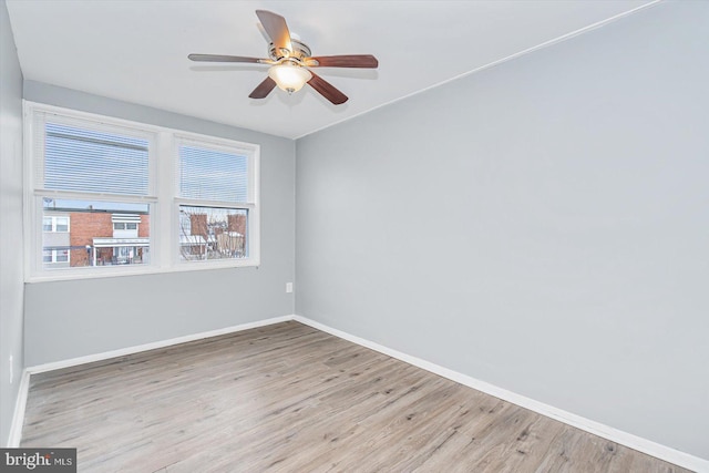 empty room with a ceiling fan, baseboards, and wood finished floors