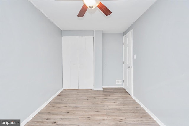 unfurnished bedroom featuring a closet, wood finished floors, a ceiling fan, and baseboards