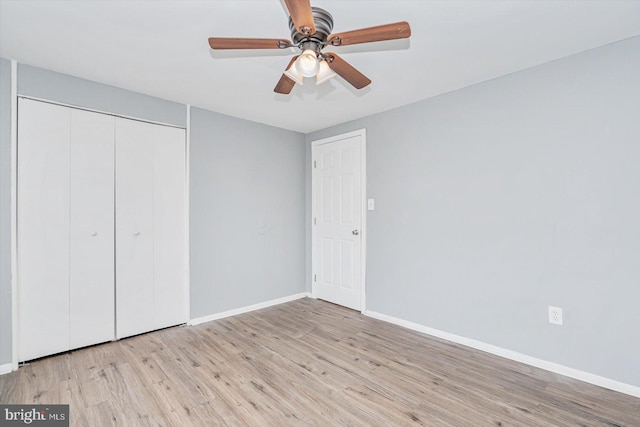 unfurnished bedroom featuring a ceiling fan, a closet, light wood-style flooring, and baseboards