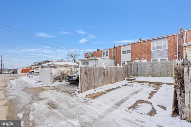 yard covered in snow with a residential view and fence