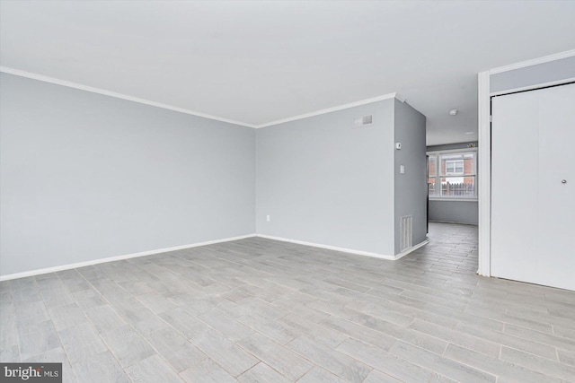 spare room featuring baseboards, crown molding, visible vents, and light wood finished floors