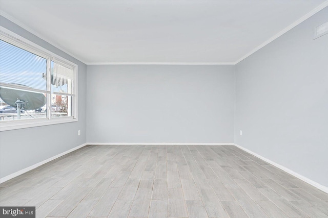 empty room featuring crown molding, light wood finished floors, and baseboards