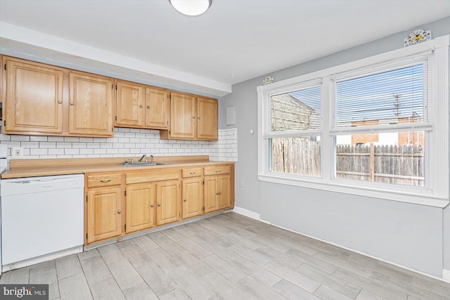 kitchen featuring a sink, backsplash, light countertops, and dishwasher