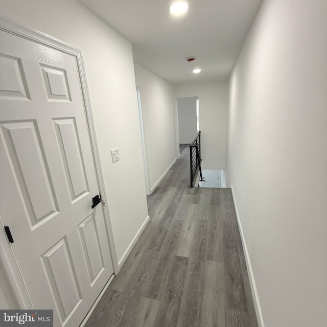 hallway featuring recessed lighting, baseboards, wood finished floors, and an upstairs landing