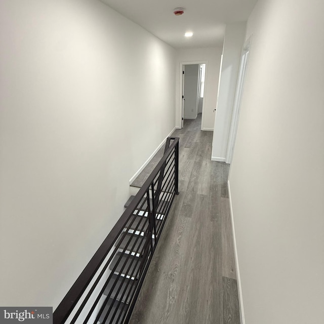 hallway with wood finished floors, an upstairs landing, and baseboards