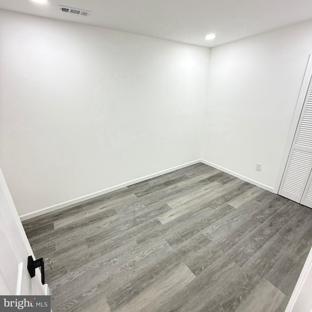 empty room featuring dark wood-type flooring, recessed lighting, visible vents, and baseboards