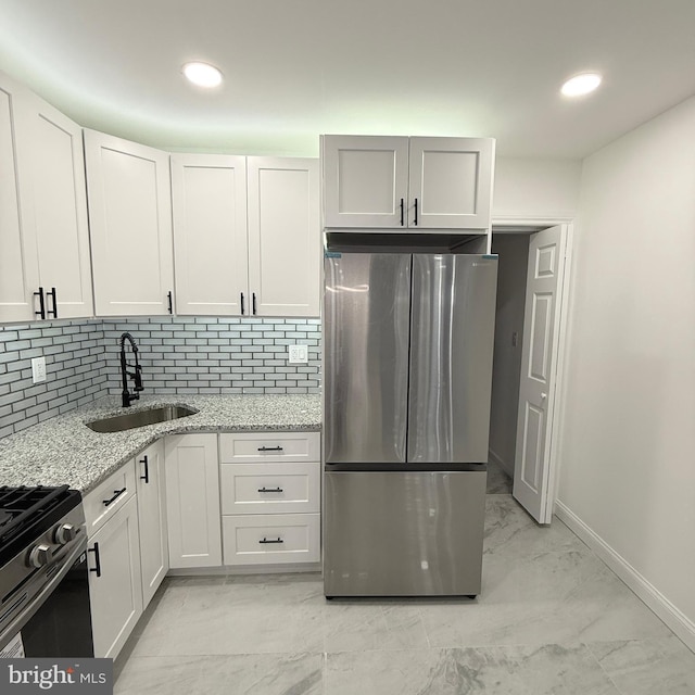 kitchen featuring appliances with stainless steel finishes, light stone counters, a sink, marble finish floor, and backsplash