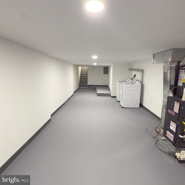 finished below grade area featuring heating unit, baseboards, stairway, and washing machine and clothes dryer