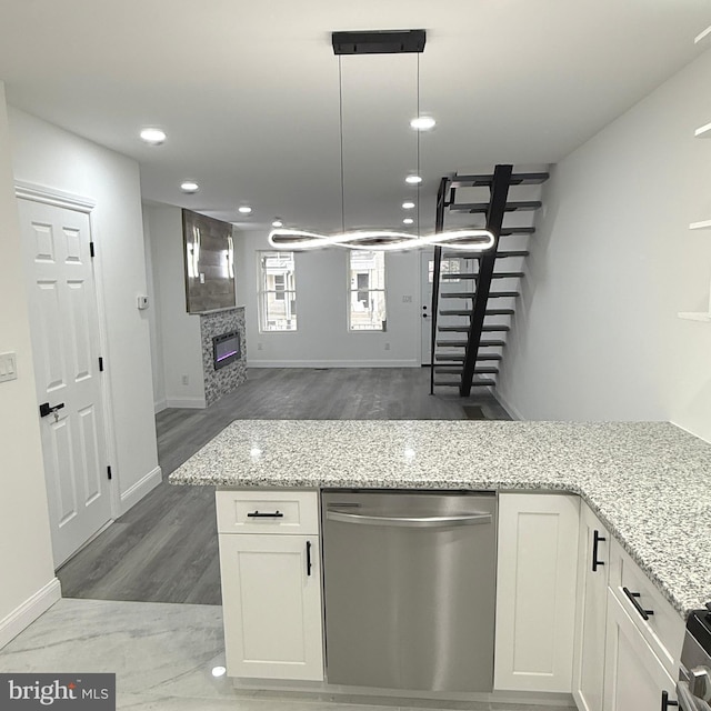 kitchen with light stone countertops, a fireplace, appliances with stainless steel finishes, and white cabinets