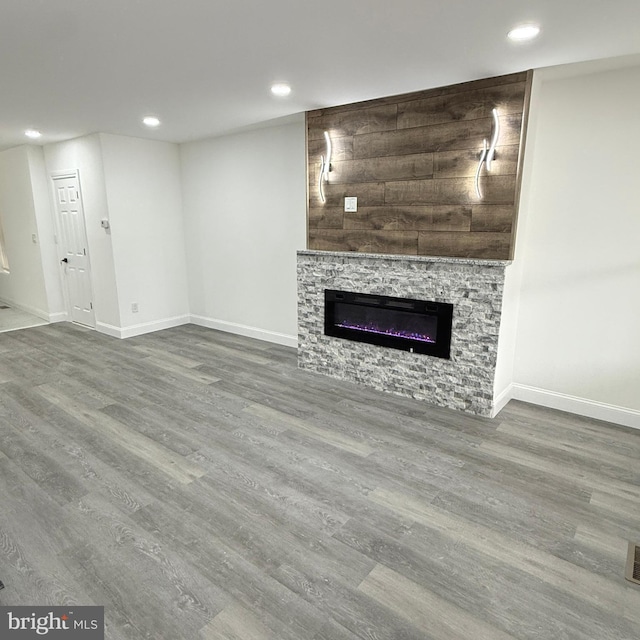 unfurnished living room with a fireplace, baseboards, wood finished floors, and recessed lighting