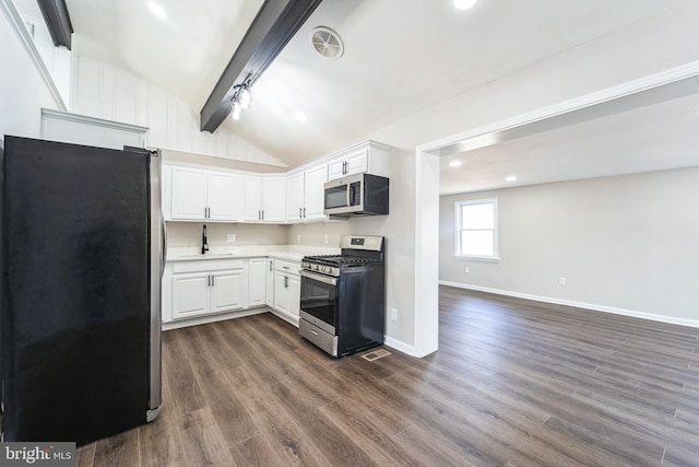 kitchen with dark wood-type flooring, stainless steel appliances, white cabinets, light countertops, and vaulted ceiling with beams