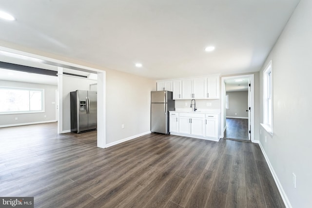 kitchen with freestanding refrigerator, a sink, white cabinets, stainless steel refrigerator with ice dispenser, and open floor plan