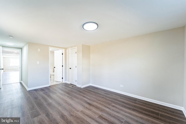 spare room featuring dark wood finished floors and baseboards