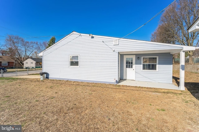 back of property with a lawn and fence