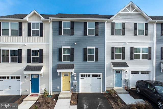 multi unit property with driveway, an attached garage, and a shingled roof