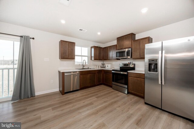 kitchen with light countertops, a sink, light wood finished floors, appliances with stainless steel finishes, and visible vents