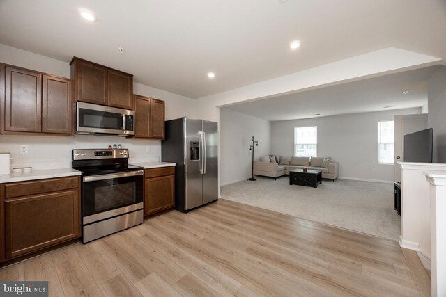 kitchen with light countertops, recessed lighting, appliances with stainless steel finishes, light wood-type flooring, and open floor plan