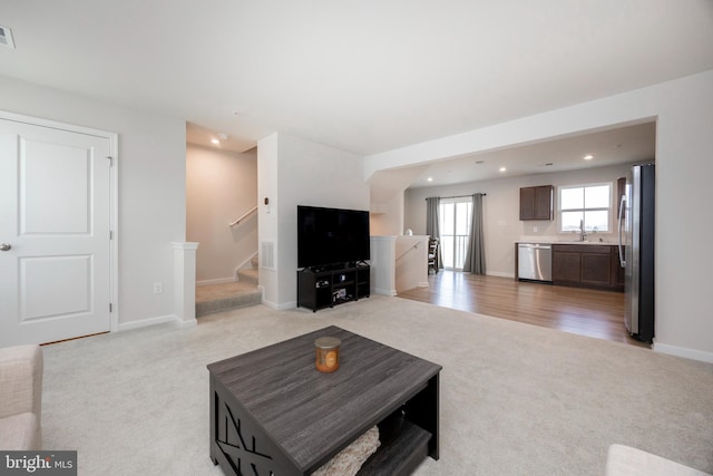 living area with stairway, light carpet, baseboards, visible vents, and recessed lighting