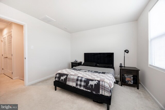 bedroom with baseboards, light colored carpet, and visible vents