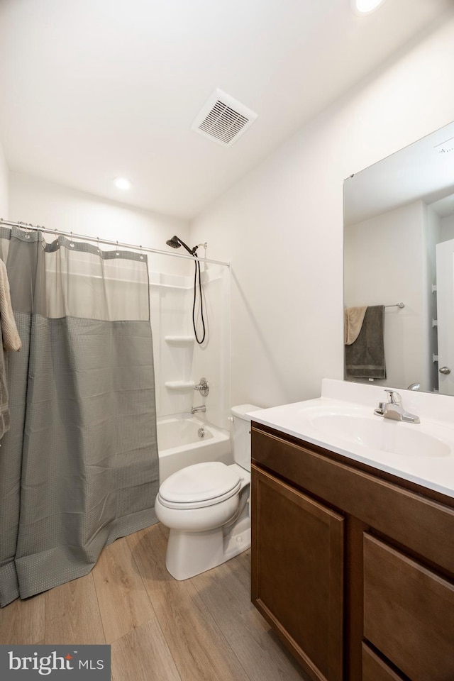 bathroom featuring toilet, vanity, wood finished floors, visible vents, and shower / bath combination with curtain