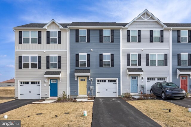multi unit property featuring driveway, an attached garage, and roof with shingles