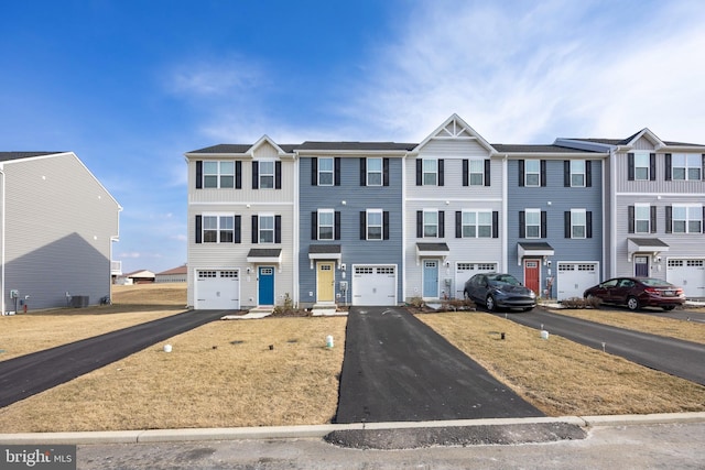 multi unit property with driveway, an attached garage, and central AC