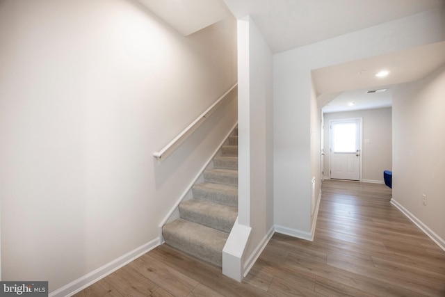 staircase featuring baseboards and wood finished floors