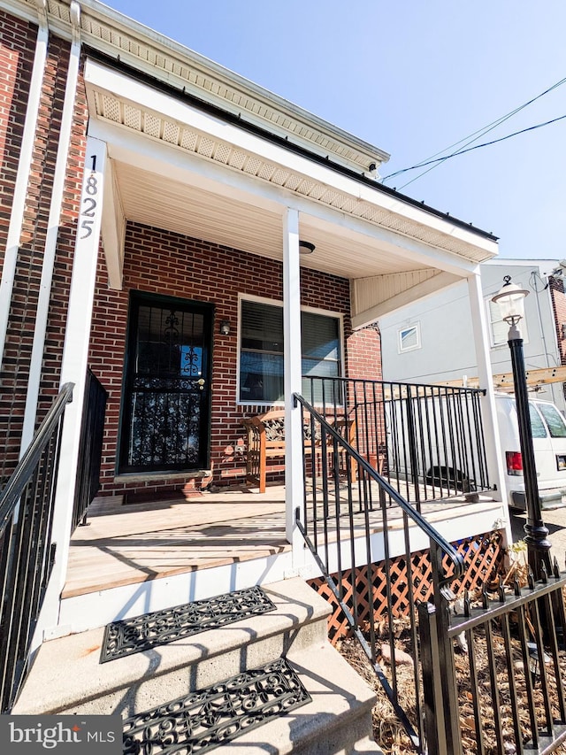 property entrance featuring covered porch and brick siding