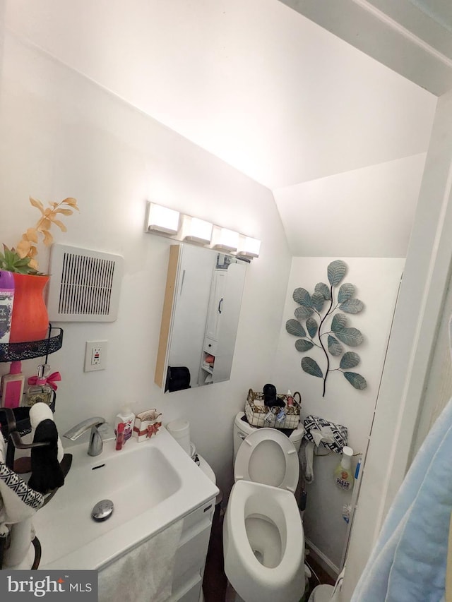 bathroom with vaulted ceiling, visible vents, a sink, and toilet