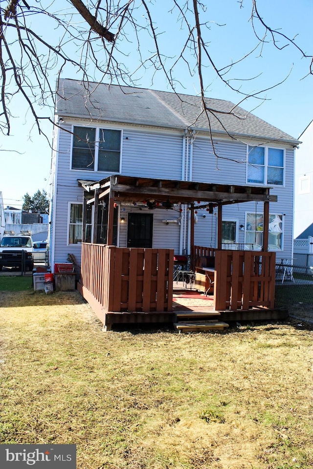 back of property featuring a wooden deck, fence, roof with shingles, and a yard