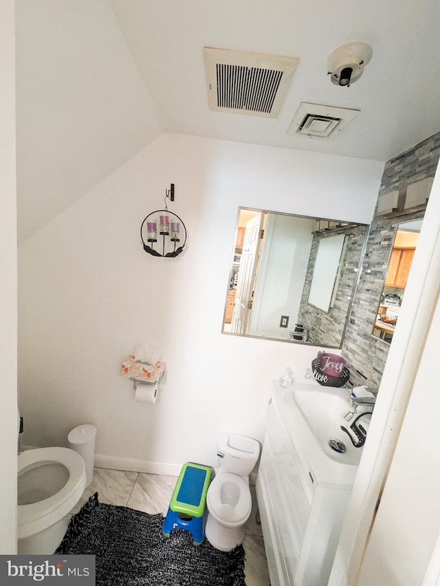 half bathroom featuring toilet, marble finish floor, vaulted ceiling, and visible vents