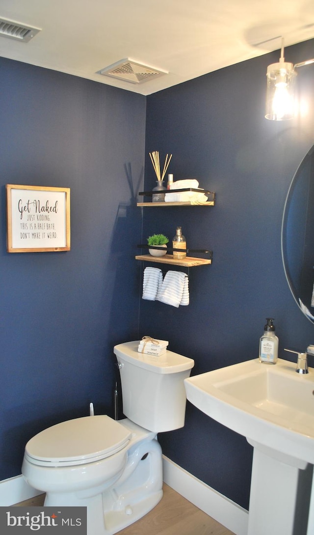 bathroom with visible vents, toilet, baseboards, and wood finished floors