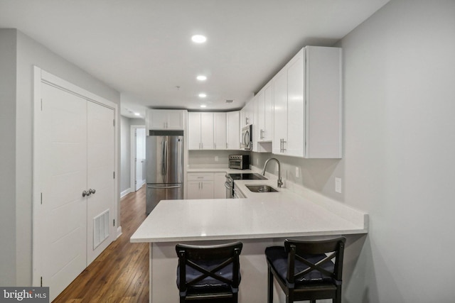 kitchen with stainless steel appliances, dark wood-type flooring, visible vents, white cabinetry, and light countertops