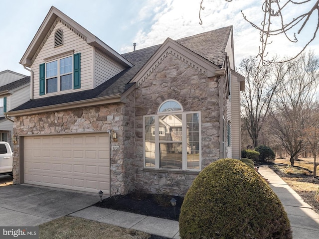 view of front of house featuring stone siding, concrete driveway, a garage, and a shingled roof