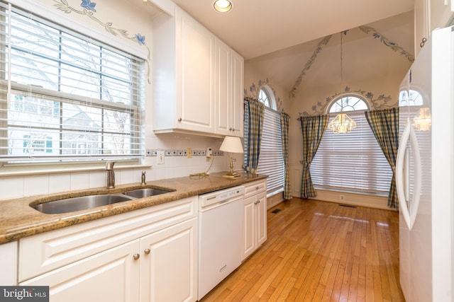 kitchen featuring light wood-style flooring, a sink, tasteful backsplash, white cabinetry, and white appliances