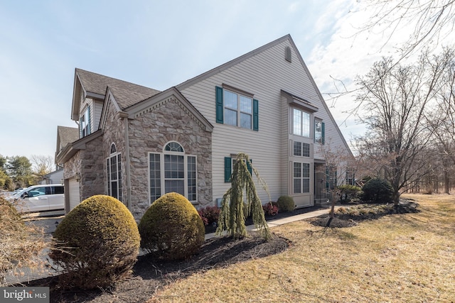 view of front of home featuring a garage, stone siding, a front lawn, and a shingled roof