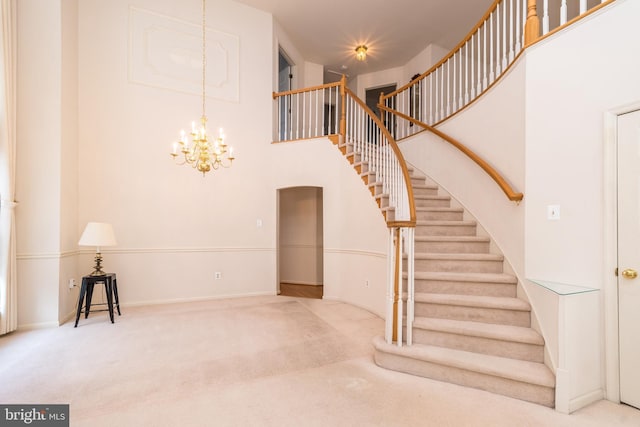 stairway with an inviting chandelier, baseboards, a towering ceiling, and carpet floors