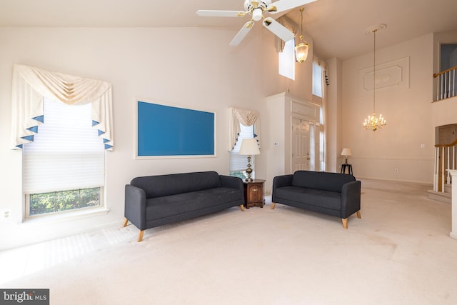 living area featuring a towering ceiling, carpet flooring, and ceiling fan with notable chandelier