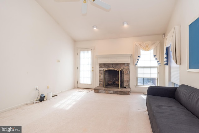 living area featuring carpet, baseboards, ceiling fan, a stone fireplace, and vaulted ceiling