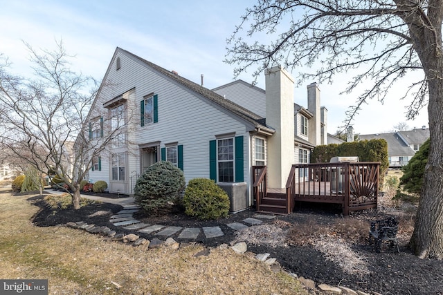 view of side of property featuring a wooden deck, central AC unit, and a chimney