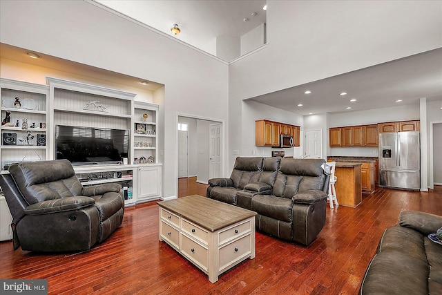 living area with dark wood-style floors, recessed lighting, and a towering ceiling