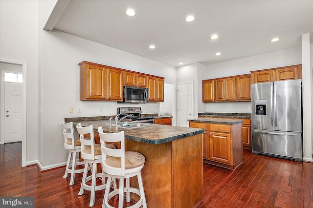 kitchen featuring a peninsula, appliances with stainless steel finishes, dark countertops, and brown cabinets