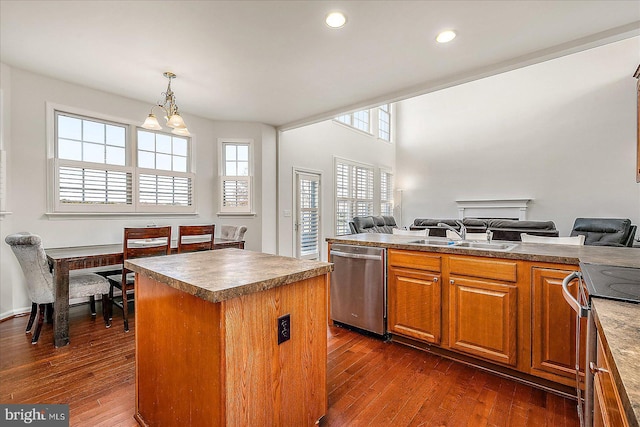 kitchen with stainless steel appliances, a center island, dark wood-type flooring, and a sink