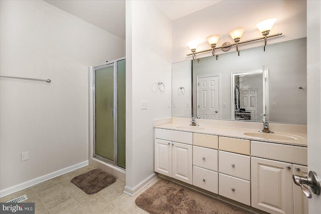 bathroom featuring double vanity, a stall shower, and a sink