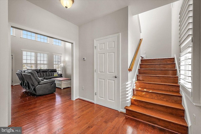 foyer entrance featuring wood-type flooring, stairway, and baseboards