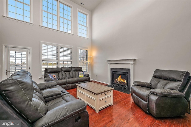 living room featuring a fireplace with flush hearth, visible vents, and dark wood finished floors