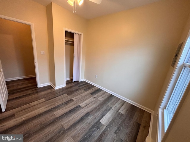 unfurnished bedroom with dark wood-style flooring, a closet, and baseboards