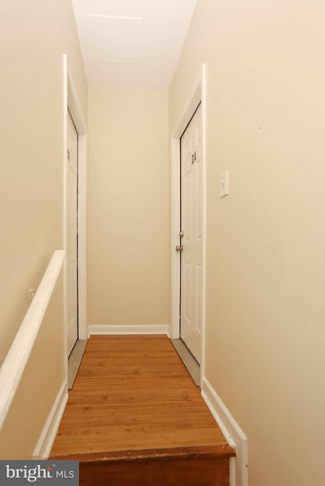 corridor featuring baseboards and light wood finished floors