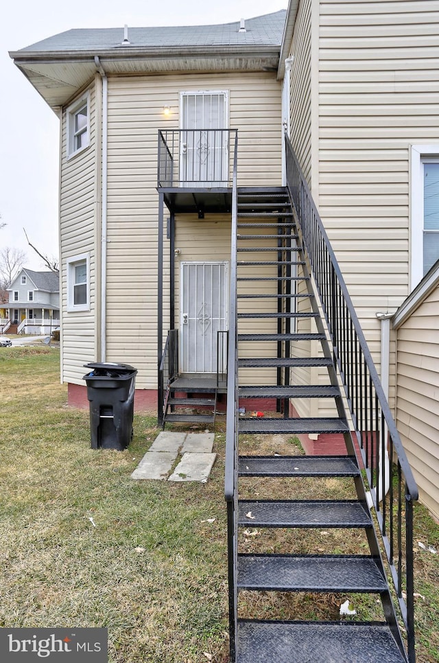 doorway to property with a balcony and a lawn